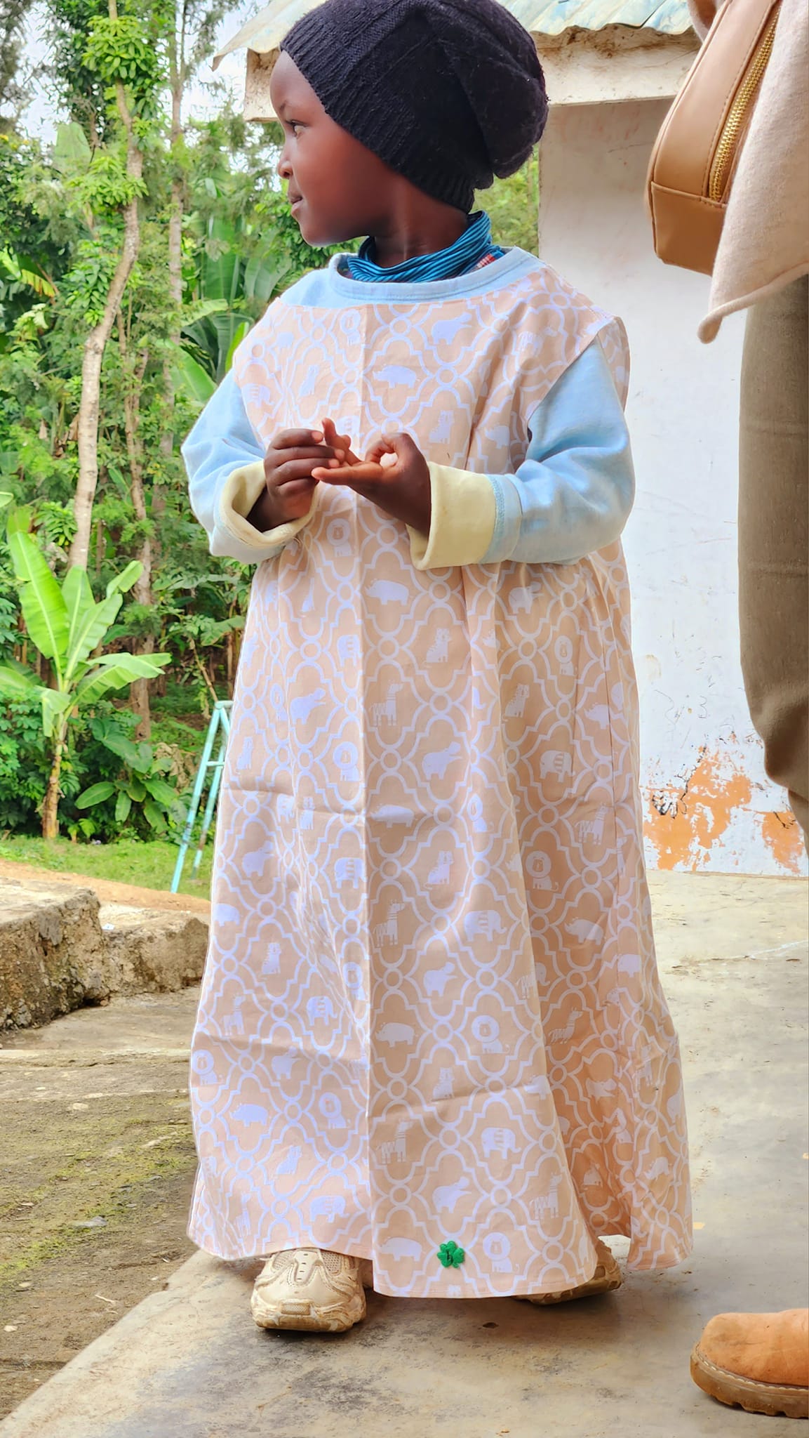 A young girl wearing a pillowcase dress with a clover embroidered.